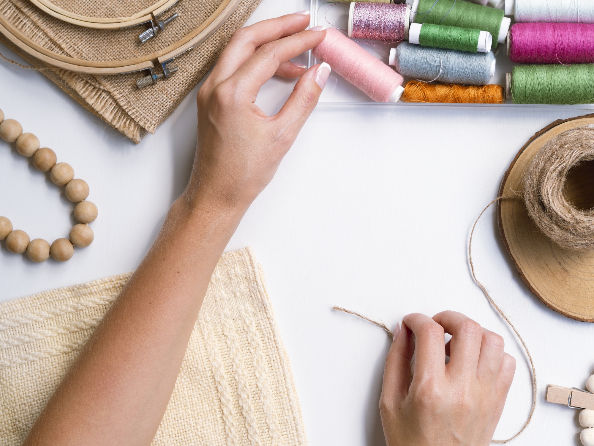 artisan hands threading needle over fabric